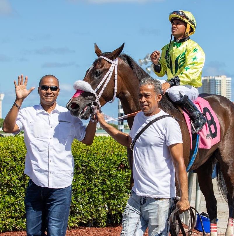 Danielle's father waving beside the winning horse and jockey in the winner's circle